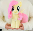 Load image into Gallery viewer, Plush toy resembling a character with pink hair and a pink bow held by a person wearing a white sweater.