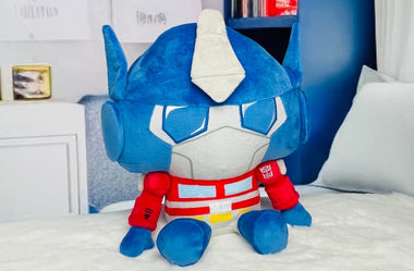 Load image into Gallery viewer, Blue and white robot plush toy with red accents on a bed