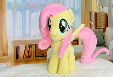 Load image into Gallery viewer, Plush toy of a yellow pony with pink hair and tail on a bed