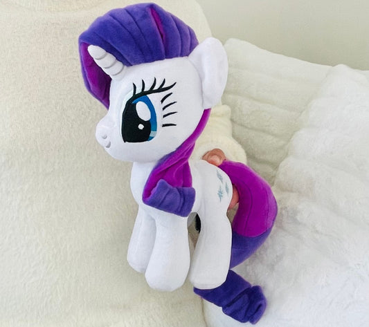 Plush toy resembling a character with a purple mane and outfit on a white background