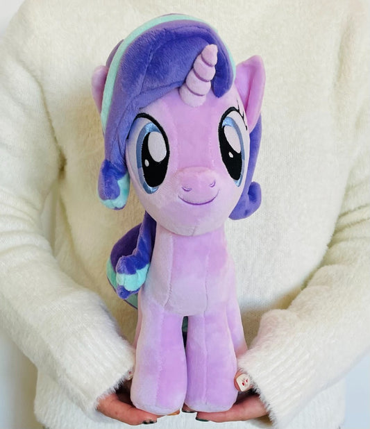 Plush toy unicorn held by a person wearing a white sweater