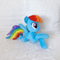 Load image into Gallery viewer, Plush toy of a blue pony with rainbow mane and tail on a white textured background