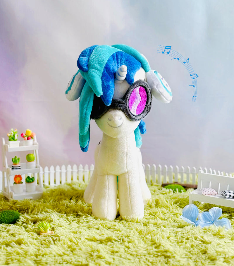 Plush toy with blue hair and goggles on a grassy area with a blurred background
