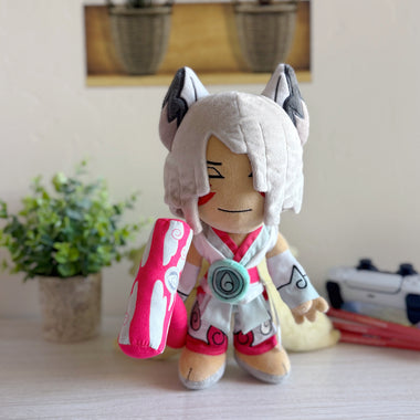 Load image into Gallery viewer, Plush toy with fox-like design on a surface with a plant and camera in the background