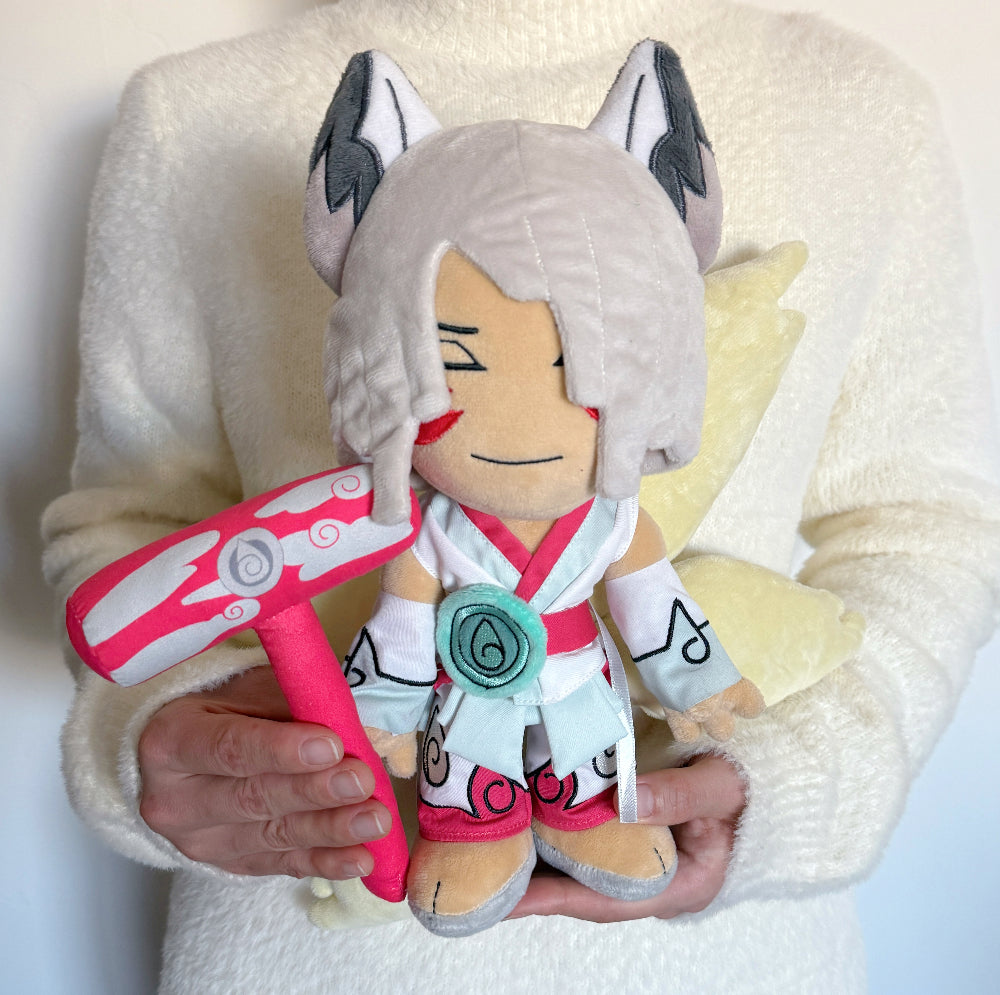 Plush toy resembling a character with fox-like features, holding a pink weapon, against a white background.