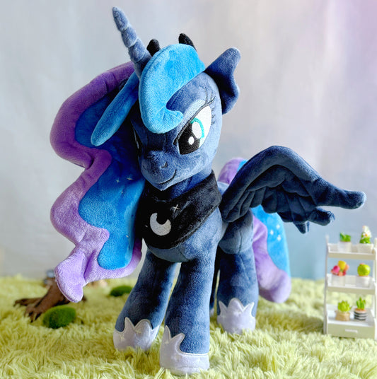 Blue and purple plush toy with wings on a yellow surface