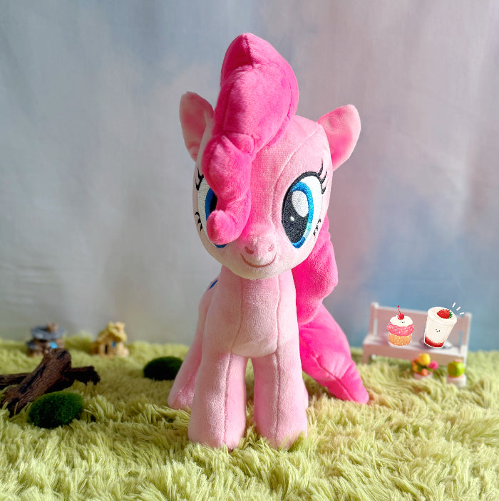 Pink plush toy on a grass-like surface with a blurred background