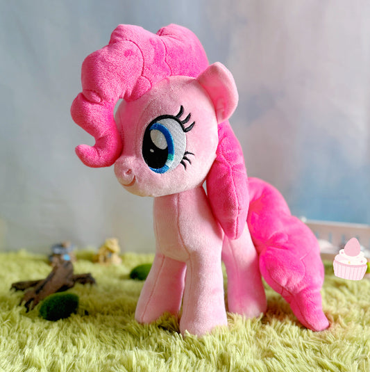 Pink plush toy on a grass-like surface with a blurred background