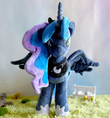 Load image into Gallery viewer, Blue and purple plush toy with a unicorn design on a grassy surface.