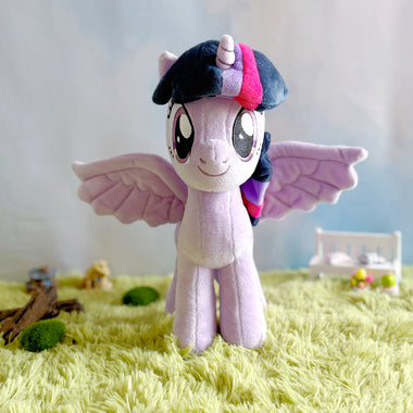 Load image into Gallery viewer, Plush toy unicorn with a colorful mane on a grass-like surface with a blurred background