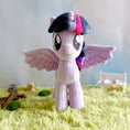 Load image into Gallery viewer, Plush toy unicorn with a colorful mane on a grass-like surface with a blurred background