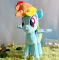 Load image into Gallery viewer, Plush toy of a character with rainbow hair on a grassy surface