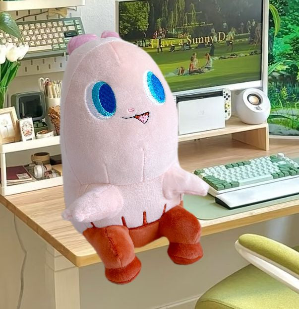 Plush toy with blue eyes on a desk in front of a computer screen