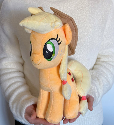 Load image into Gallery viewer, Plush toy of a cartoon pony held by a person wearing a white sweater.