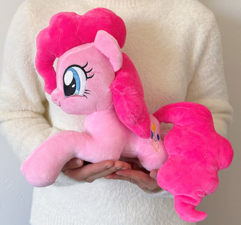 Person holding a pink plush toy with a heart-shaped mane.