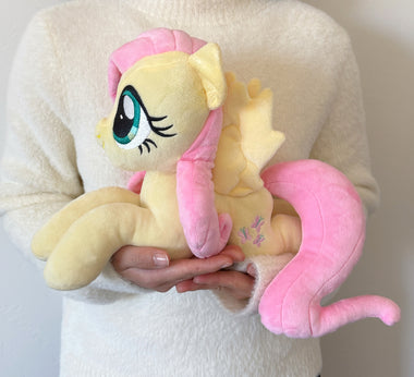Load image into Gallery viewer, Plush toy of a pink-haired pony held by a person wearing a white sweater.