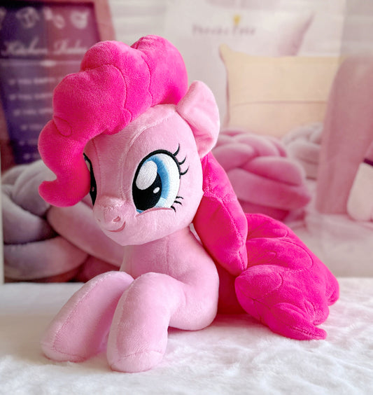 Pink plush toy with a large bow on a soft surface