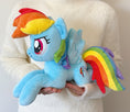 Load image into Gallery viewer, Plush toy of a blue pony with rainbow hair and tail held by a person wearing a white sweater.
