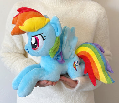 Load image into Gallery viewer, Plush toy of a blue pony with rainbow hair and tail held by a person wearing a white sweater.