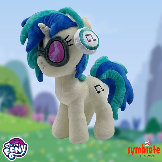 Plush toy with blue hair and goggles on a blurred nature background, featuring My Little Pony and Symbiote Studios logos.