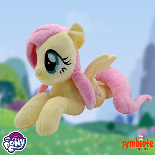 Plush toy of a pony with pink hair and wings, set against a blurred outdoor background.