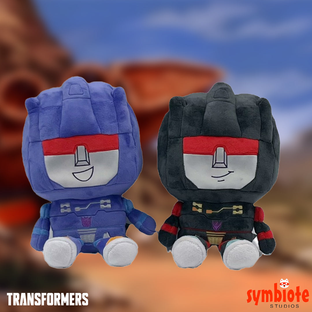 Two plush toys resembling characters from 'Transformers' with a blurred background.