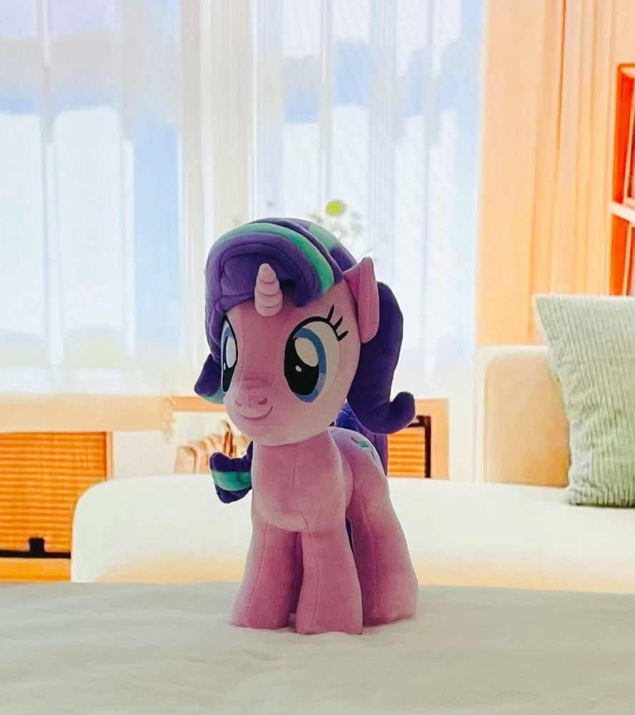 Plush toy resembling a character from 'My Little Pony' on a bed with a blurred room background