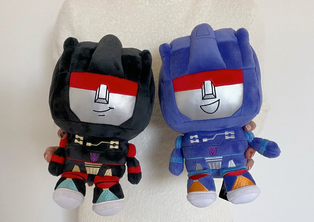 Two plush toys, one black and red, the other blue and red, on a light background.