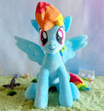 Load image into Gallery viewer, Plush toy of a blue pony with rainbow hair on a grassy surface
