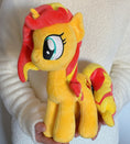 Load image into Gallery viewer, Plush toy of a yellow pony with red mane held in hands against a white background

