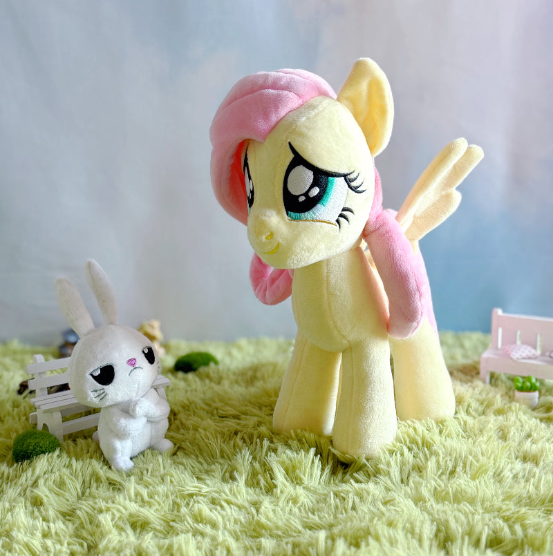 Plush toy of a pony with pink hair on a green surface
