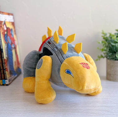 Load image into Gallery viewer, Plush toy resembling a dragon with yellow spikes on a light surface.
