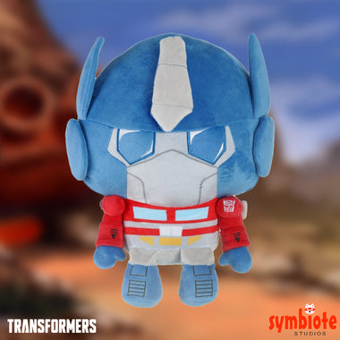 Load image into Gallery viewer, Plush toy of a robot character from Transformers with a blurred background
