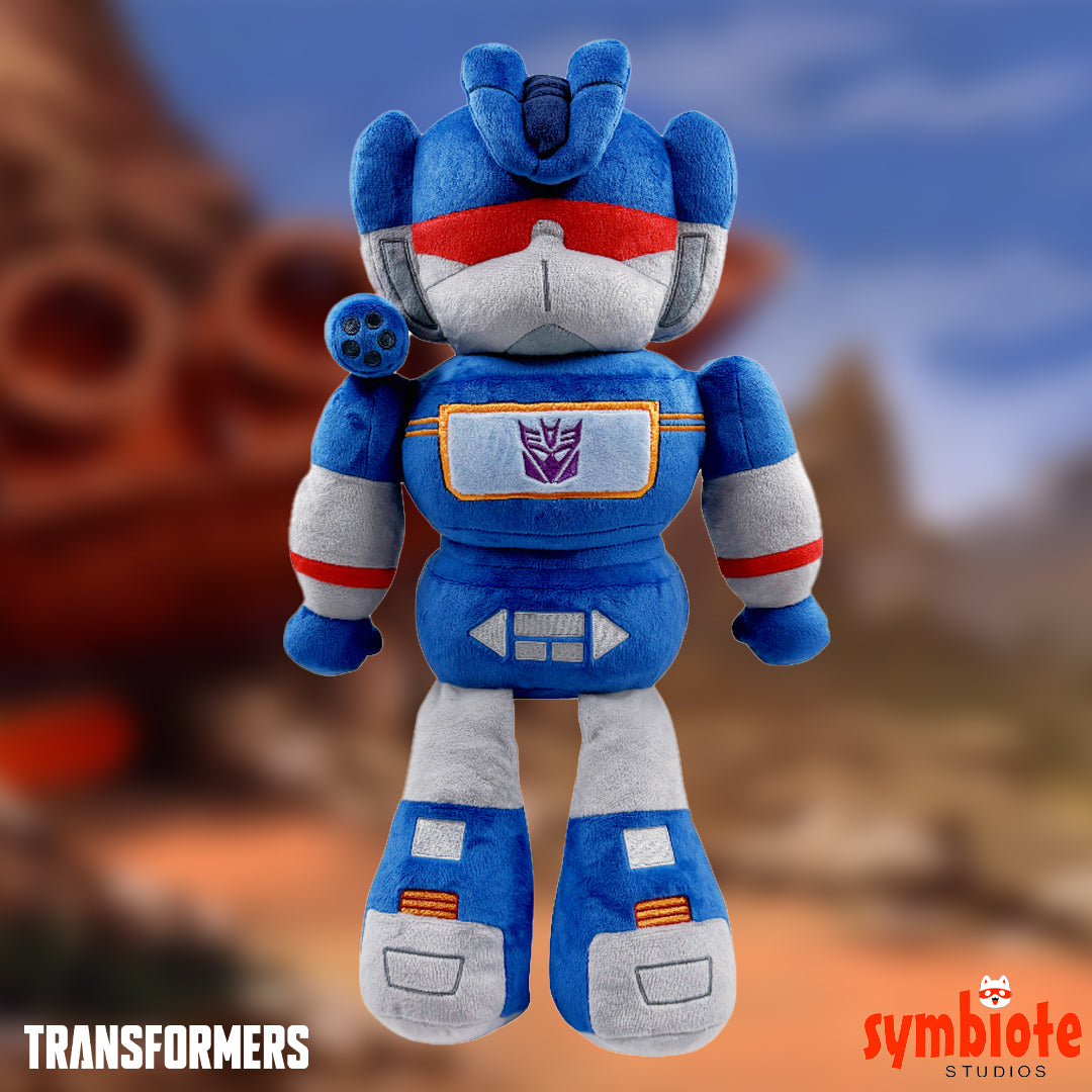Blue robot plush toy with red and white accents against a blurred natural background